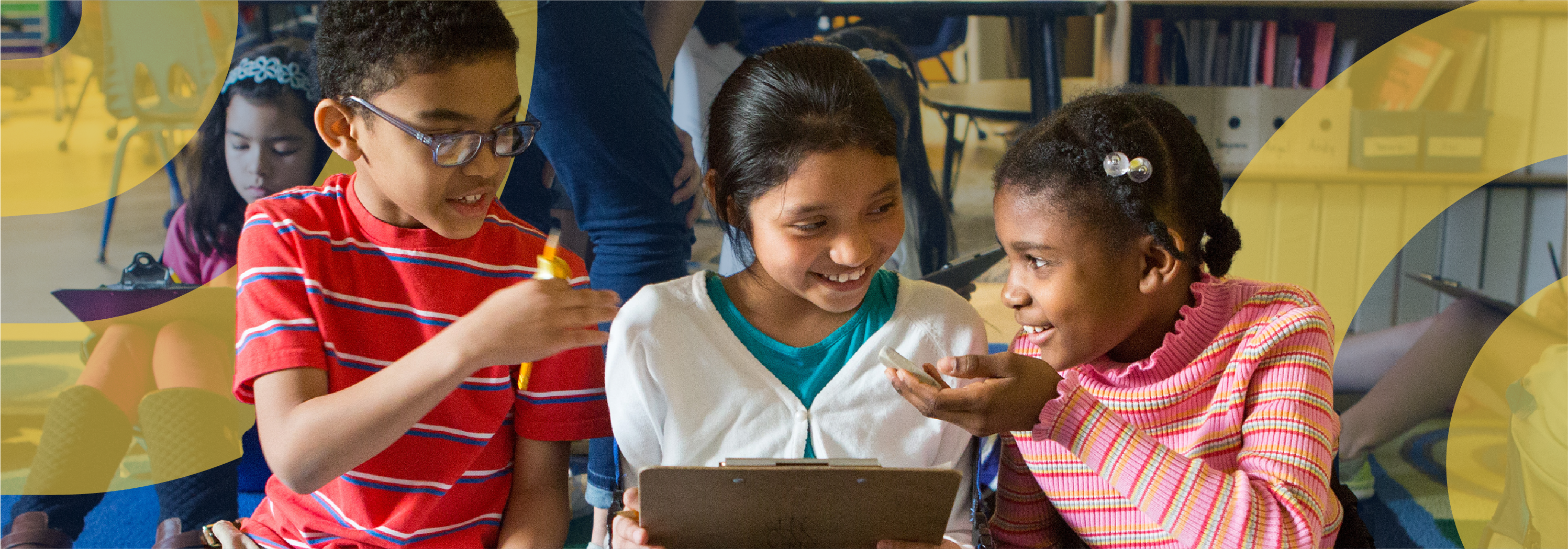 three elementary-age students interacting on the floor in a classroom